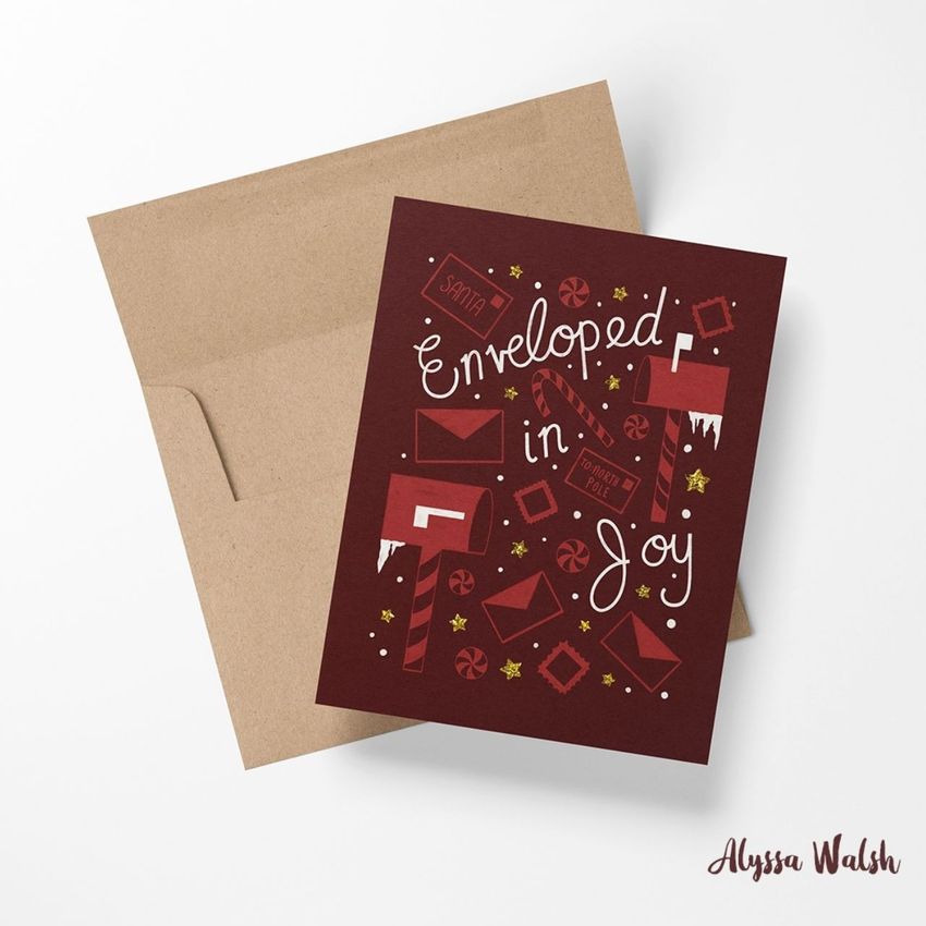 A2 card mockup featuring a burgundy greeting card with festive illustrations and handwritten text, placed on a brown envelope.