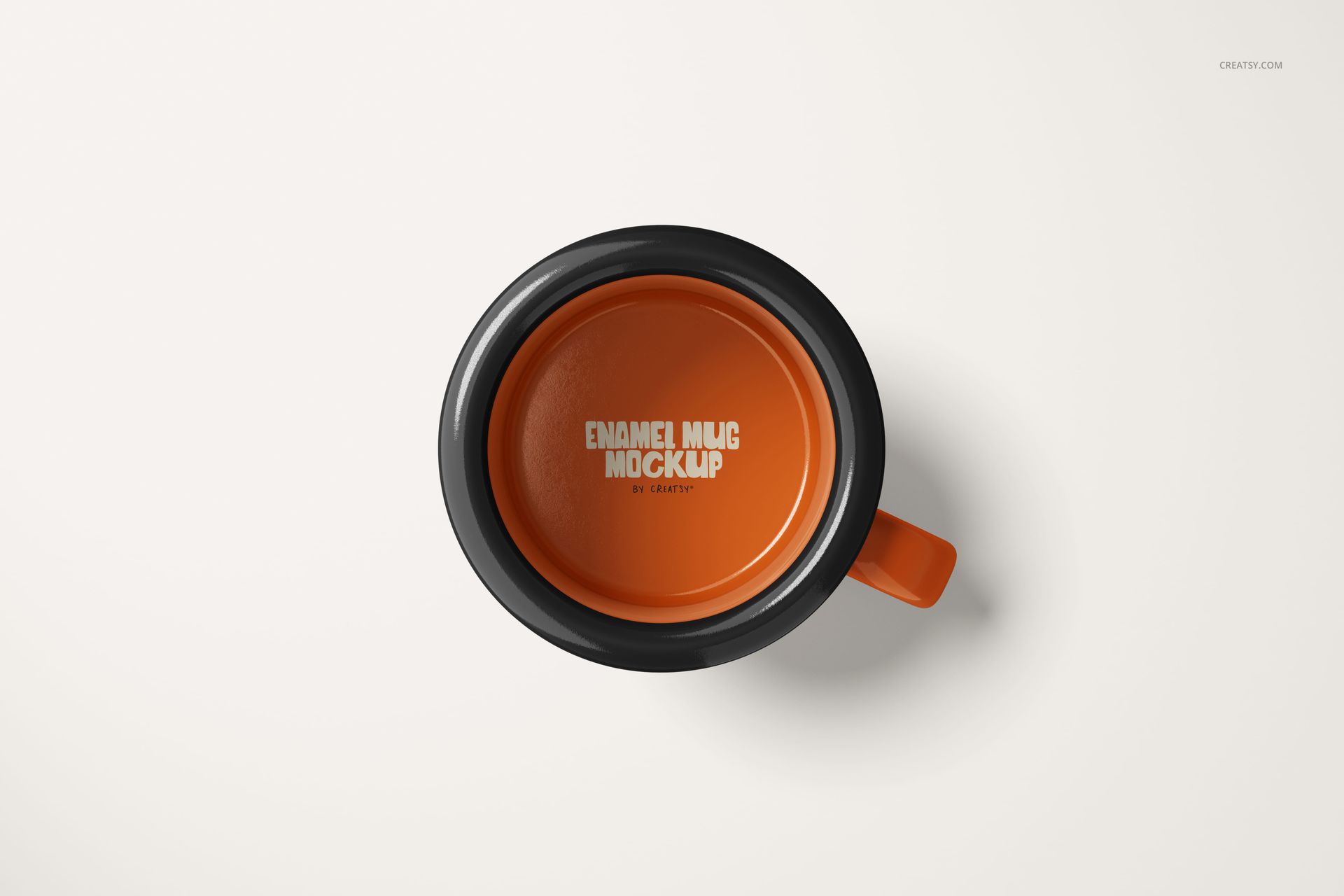 Top view of a small enamel mug with an orange interior and black rim, placed on a plain white surface.