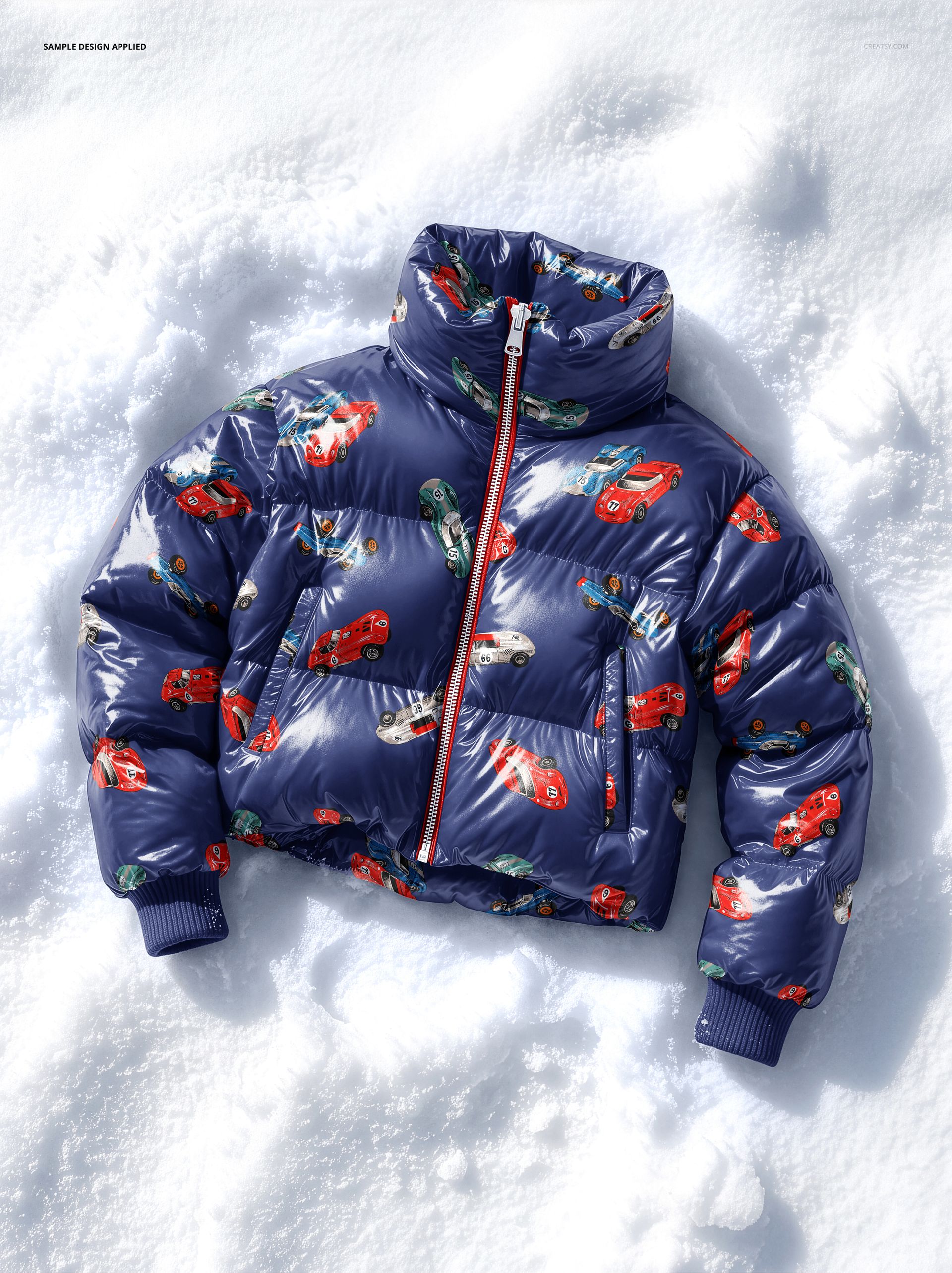 Kids puffer jacket mockup with colorful car pattern on shiny navy fabric, displayed on snow from a top view.