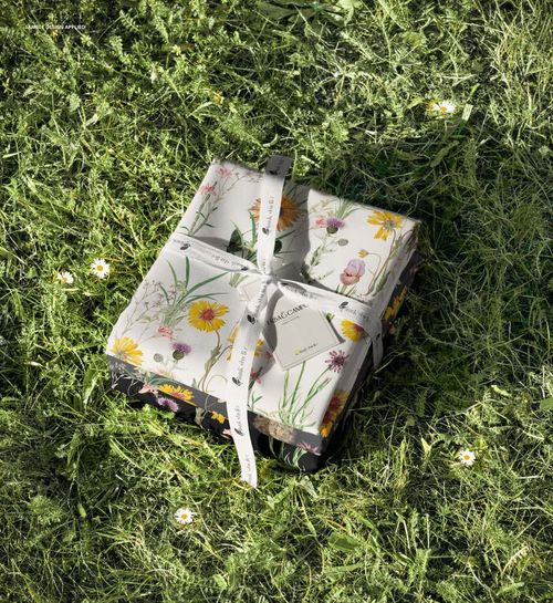 Top view of a mockup stack of fabric featuring colorful spring flowers, placed outdoors on grassy ground.