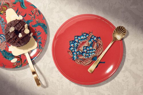 PSD mockup featuring round ceramic plates in red with ornate blue motifs, styled with a gold fork and decorative dessert.