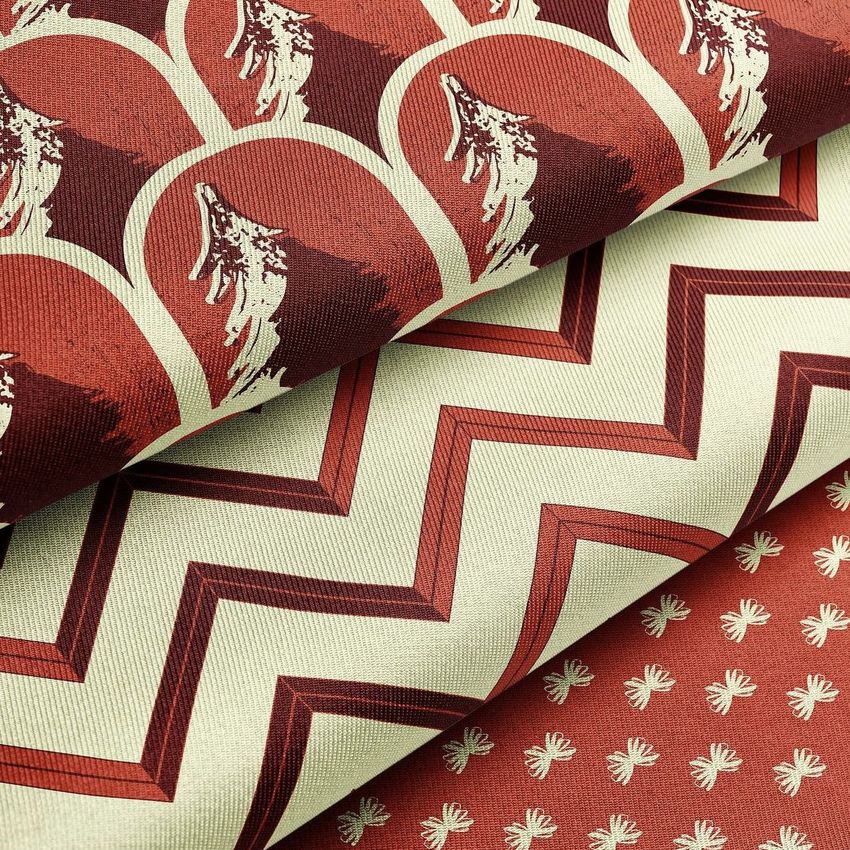 Closeup of three folded twill silk fabric mockups with red and cream patterns, including zigzags, arches, and small motifs.