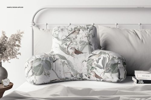 PSD mockup of a reading pillow in soft tones, decorated with leaves and birds, styled on a neatly made bed.