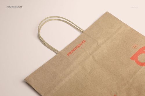 Brown kraft paper shopping bag mockup featuring printed design and sturdy handles, displayed from a top side angle.
