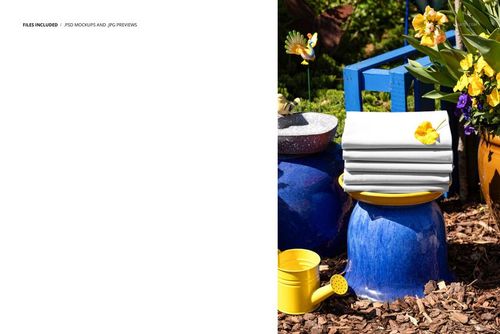 PSD mockup showing folded white fabrics with floral accents on a blue ceramic pot, with garden props and flowers.