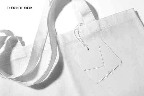Front view of a canvas tote bag mockup displaying handle details and two empty square tags on a white surface.