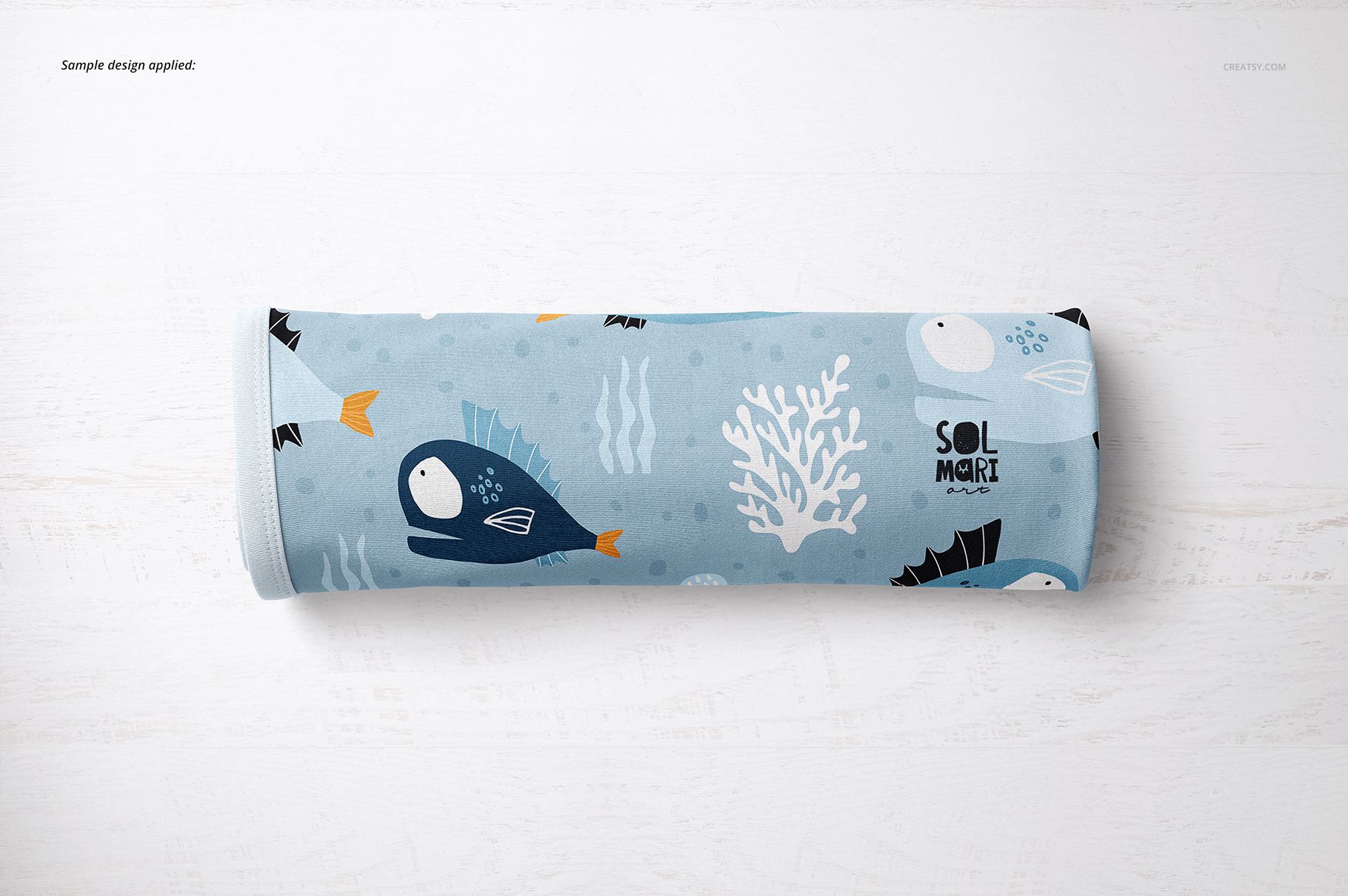 Rolled baby blanket mockup with aquatic design in blue tones, showing fish and coral on a light background.