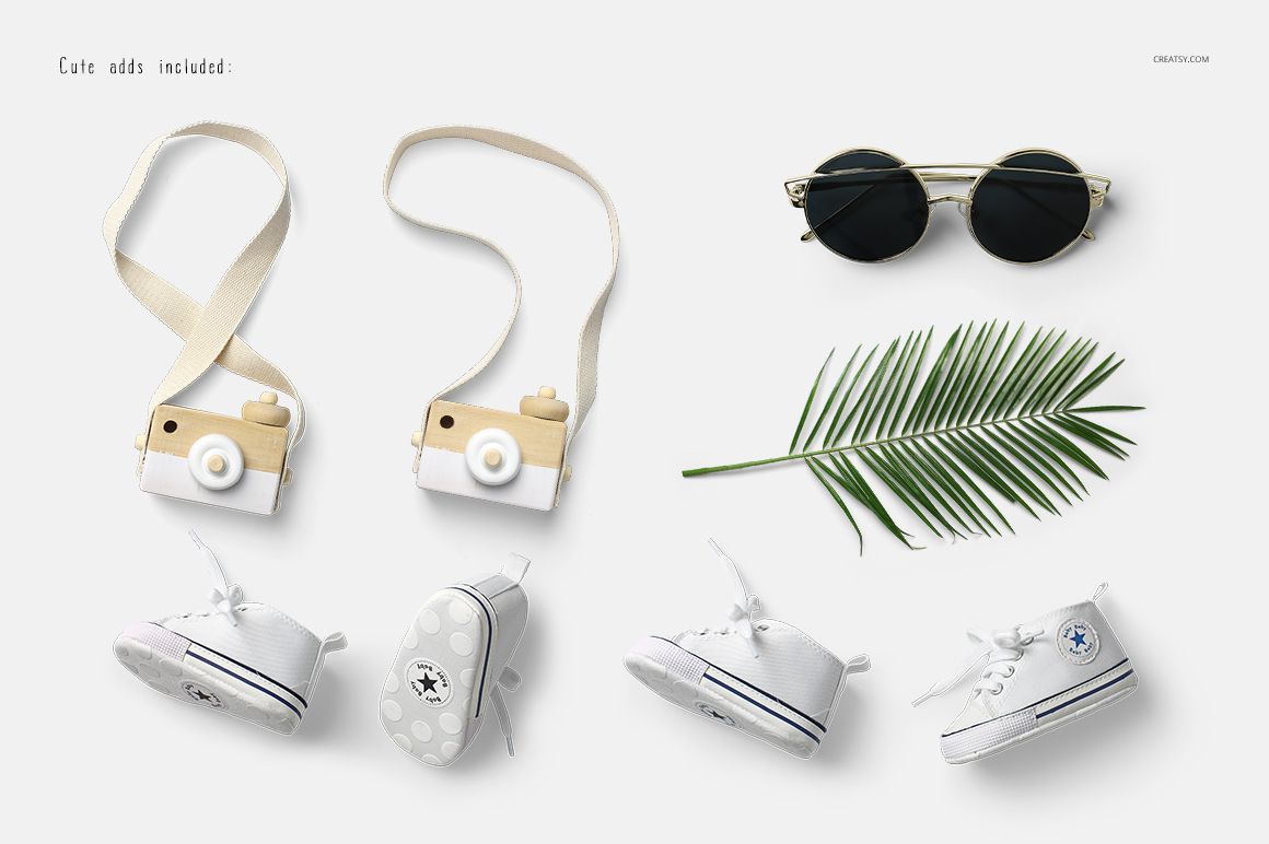 Flat lay of baby tank top mockup set with two toy cameras, white baby sneakers, sunglasses, and a green palm leaf.