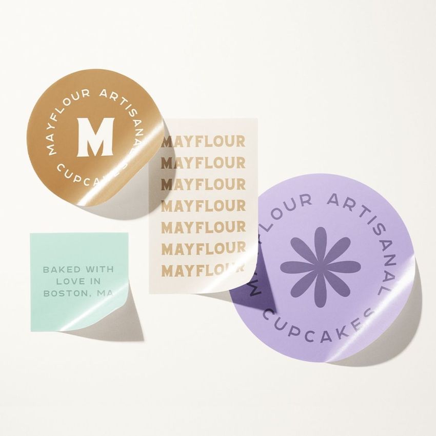Sticker mockup featuring four stickers in various shapes and pastel colors, arranged on a light surface with soft shadows.