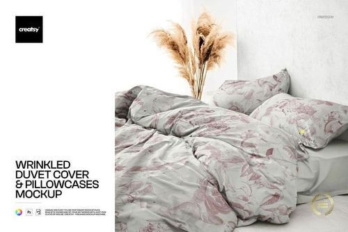 PSD mockup of a bed set with wrinkled duvet cover and pillowcases in light colors, pampas grass decor nearby.