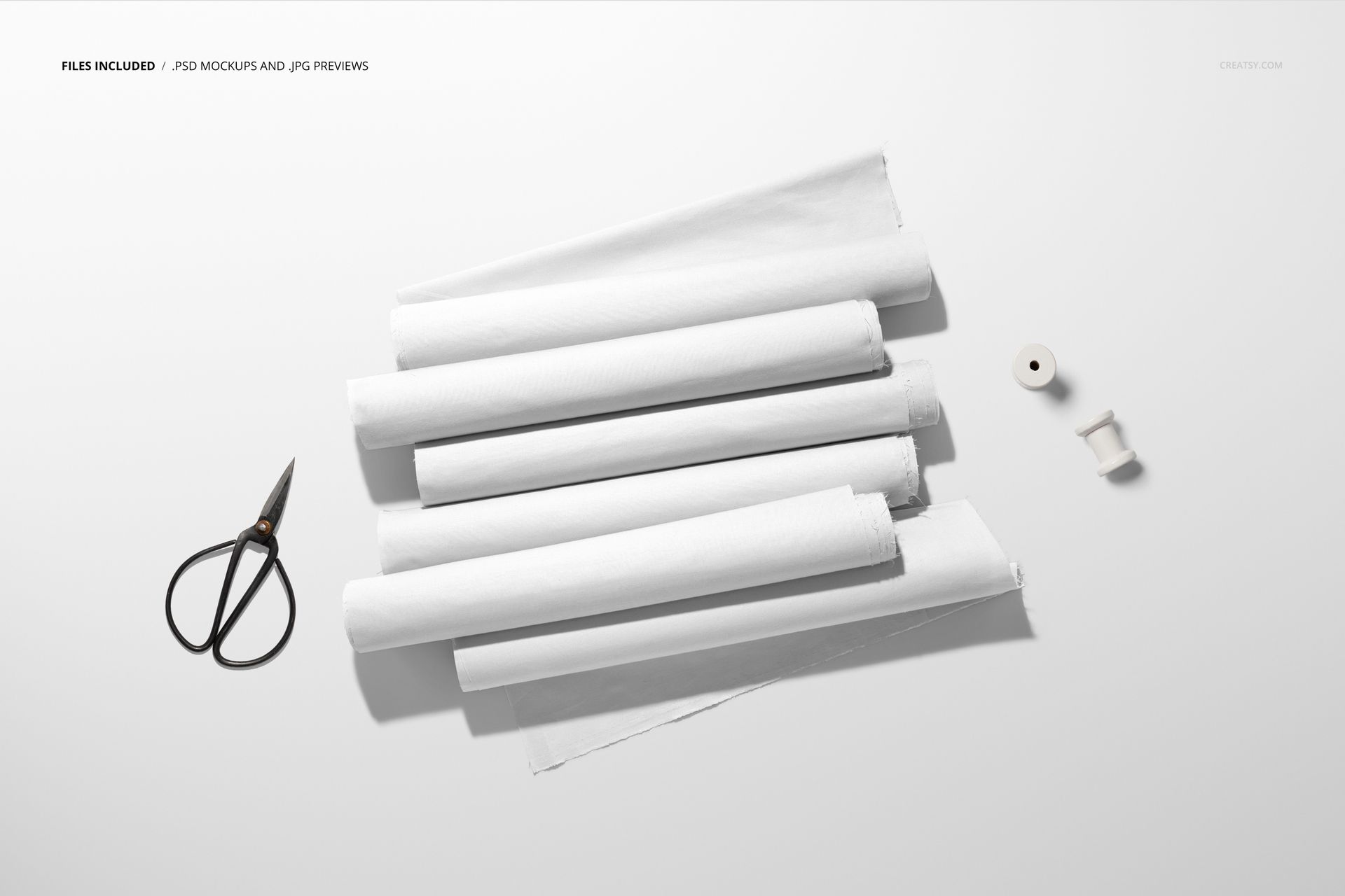 PSD mockup showing multiple white fabric rolls, some slightly unrolled, with sewing tools placed nearby.