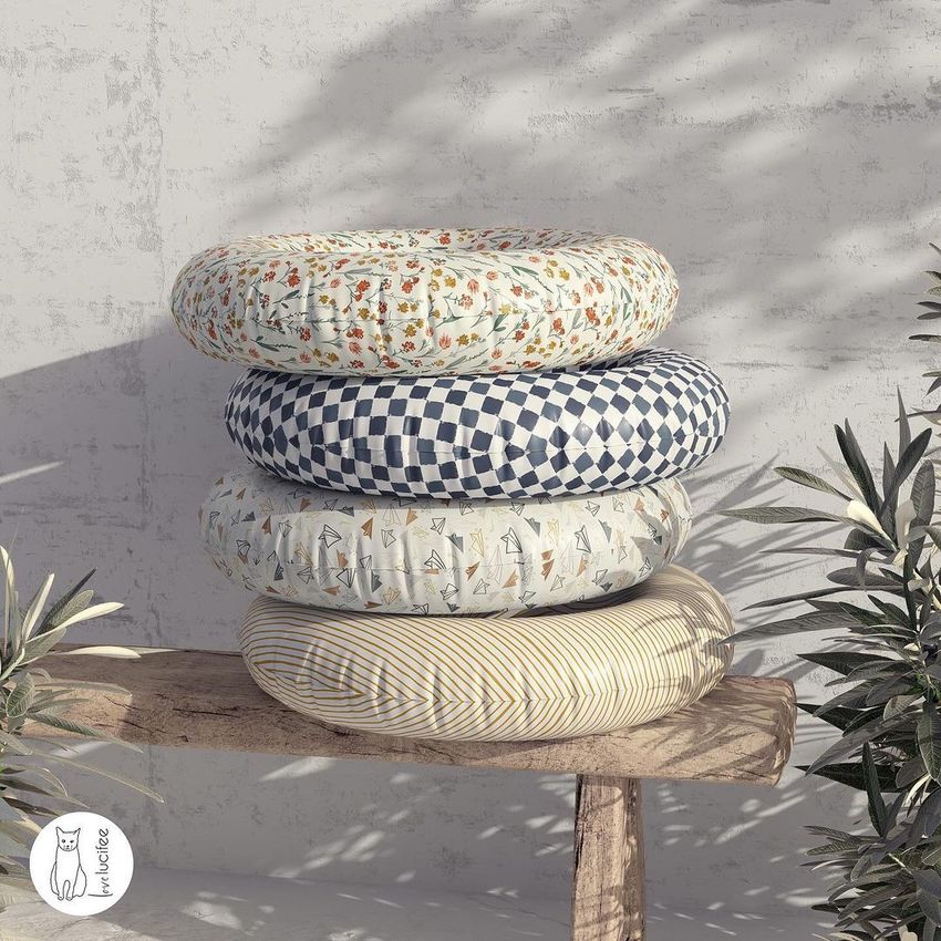 Swim ring mockup featuring four patterned inflatable rings stacked on a wooden bench, with shadows and plants nearby.