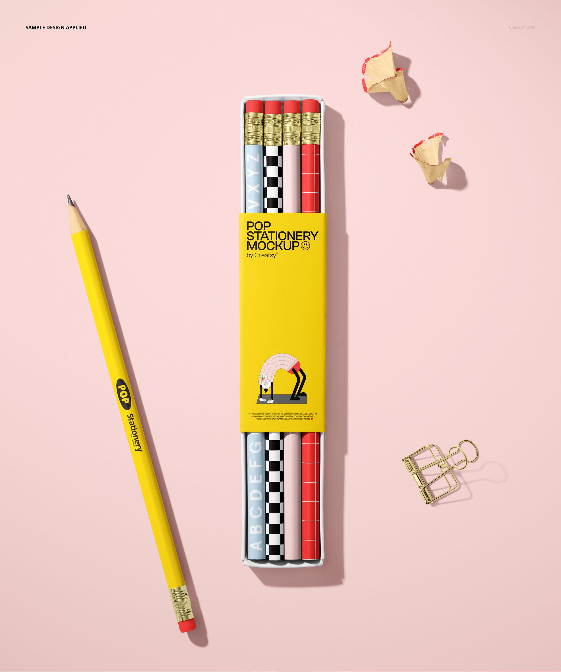 Paper pencil box mockup featuring a yellow box with assorted pencils in black, white, and red patterns on a pink surface.