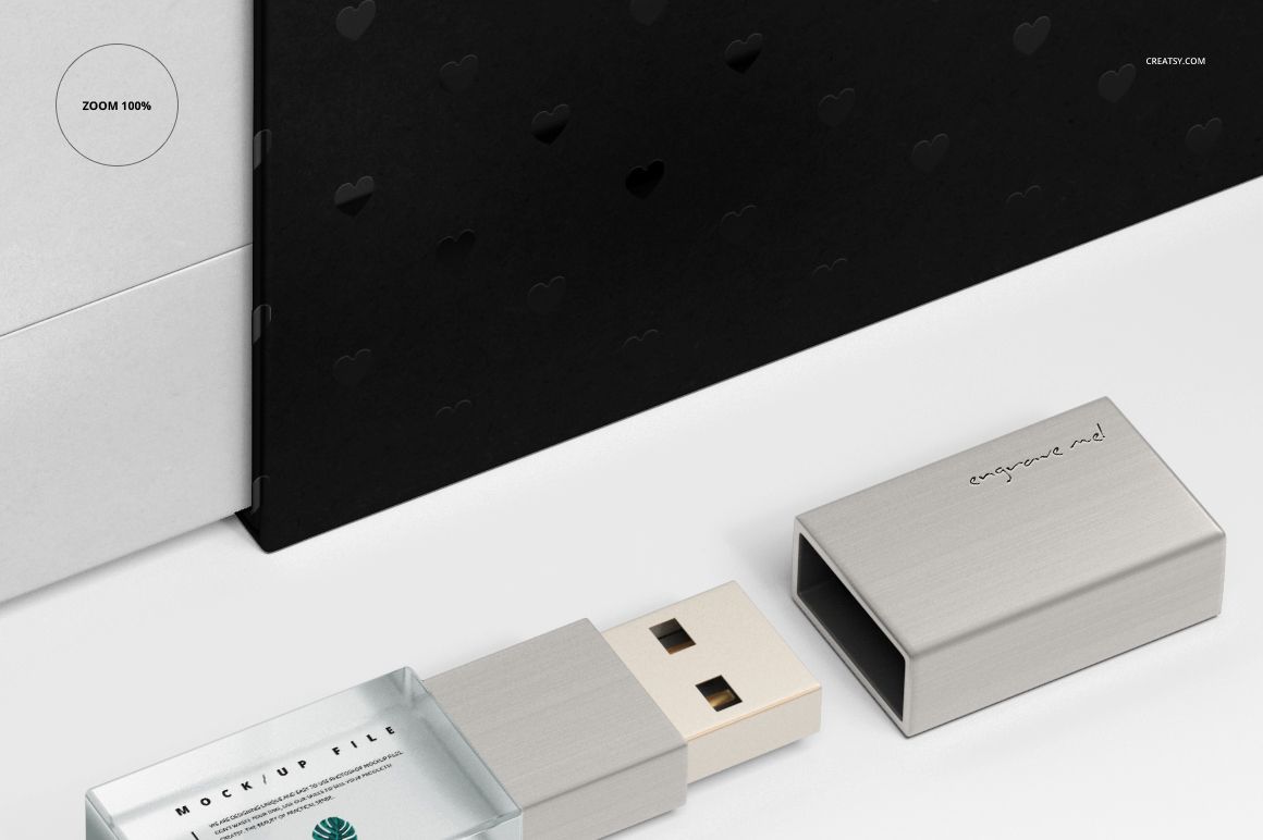 Front perspective of an acrylic USB drive mockup with a silver lid, positioned near a black slide box with embossed hearts.