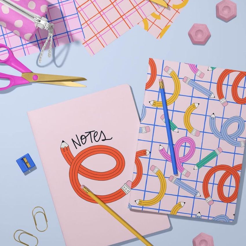 Stationery mockup featuring two A4 notebooks with playful pencil illustrations, surrounded by colorful office supplies on a pastel surface.