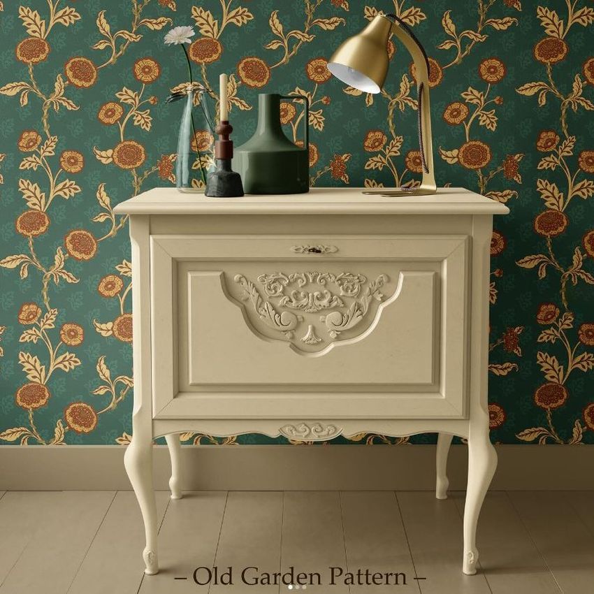 Interior scene mockup showing a vintage cream nightstand against a green wall with gold floral pattern, styled with vases and a lamp.