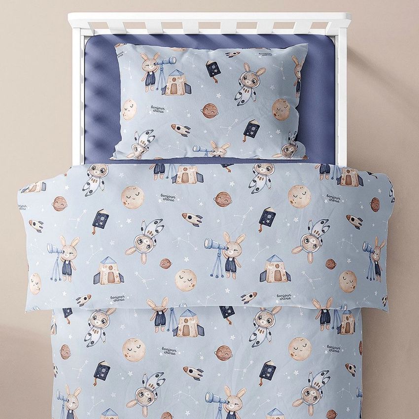 Toddler bedding mockup featuring a duvet and pillow with a blue space-themed pattern of rabbits, planets, and stars in a crib.