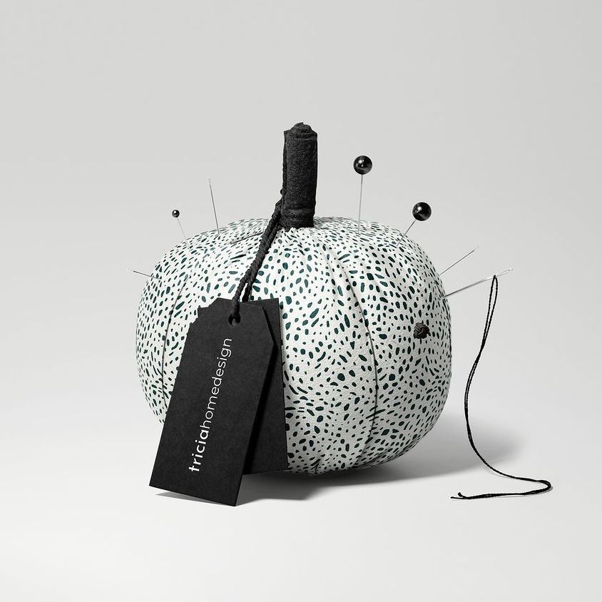 Fabric pumpkin mockup with a black and white dotted pattern, black pins, and a black tag on a light gray background.