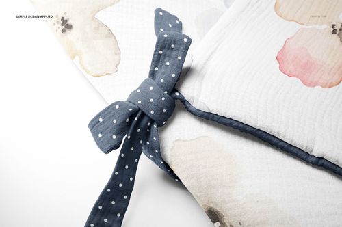 Close-up of a newborn swaddle wrap mockup with watercolor floral patterns and a blue polka dot fabric tie.