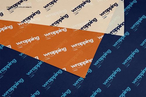 Top view of layered wrapping tissue paper mockup with beige, orange, and navy blue sheets featuring bold text design.