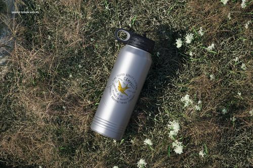 Metallic 30 oz. water bottle mockup with black screw cap, placed outdoors on patchy grass, logo visible on front.