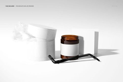 PSD mockup featuring an amber candle jar, white packaging boxes, and wick trimmer arranged on a minimalist surface.