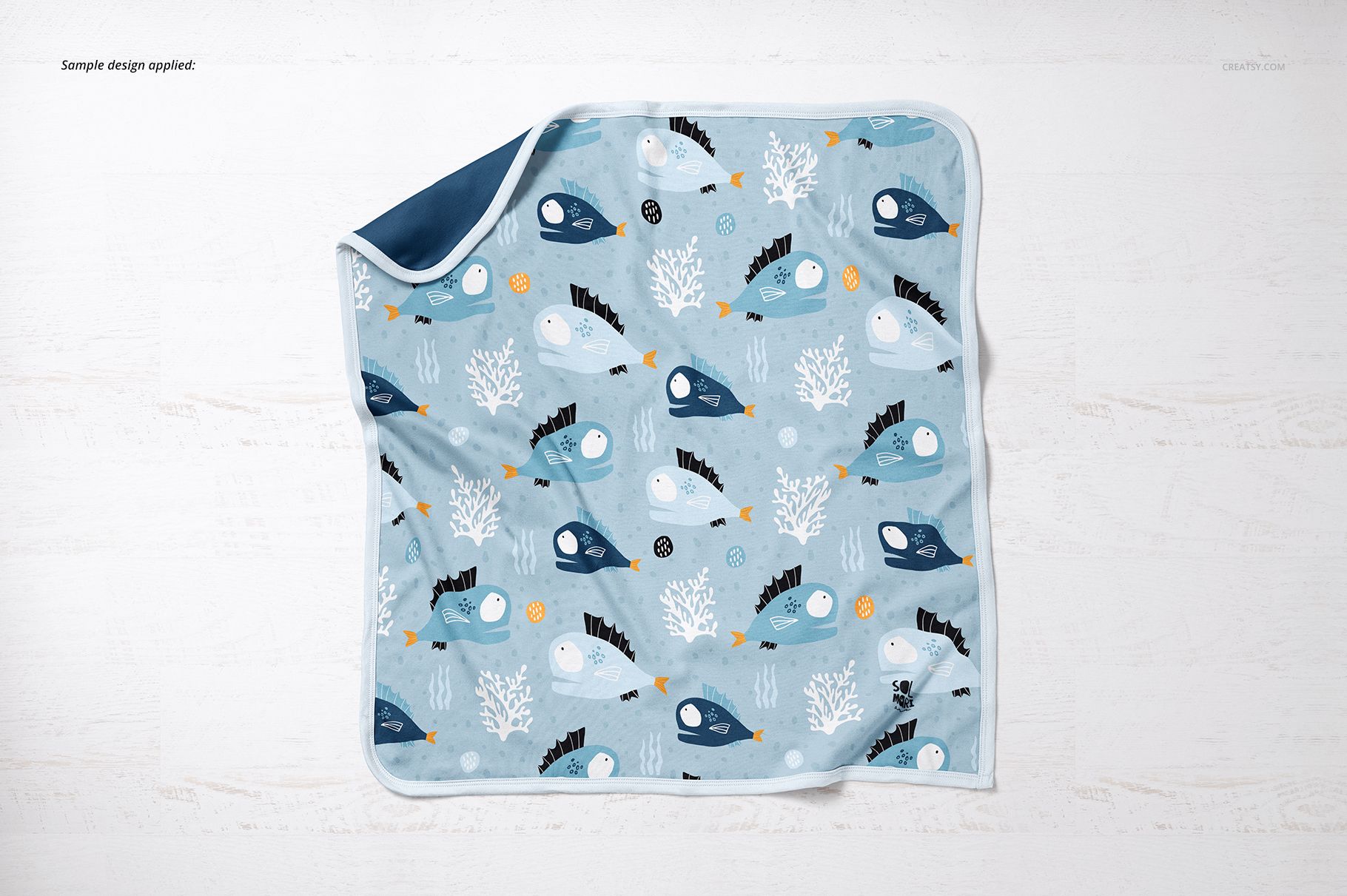Square cotton baby blanket mockup featuring playful marine animals and coral illustrations, shown from above.