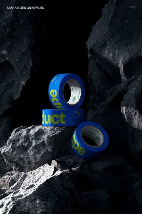 PSD mockup showing blue and yellow tape rolls placed among jagged rocks with strong shadows and highlights.