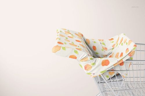 PSD mockup of a multi-use cover featuring orange peach illustrations on white fabric in a shopping cart setting.