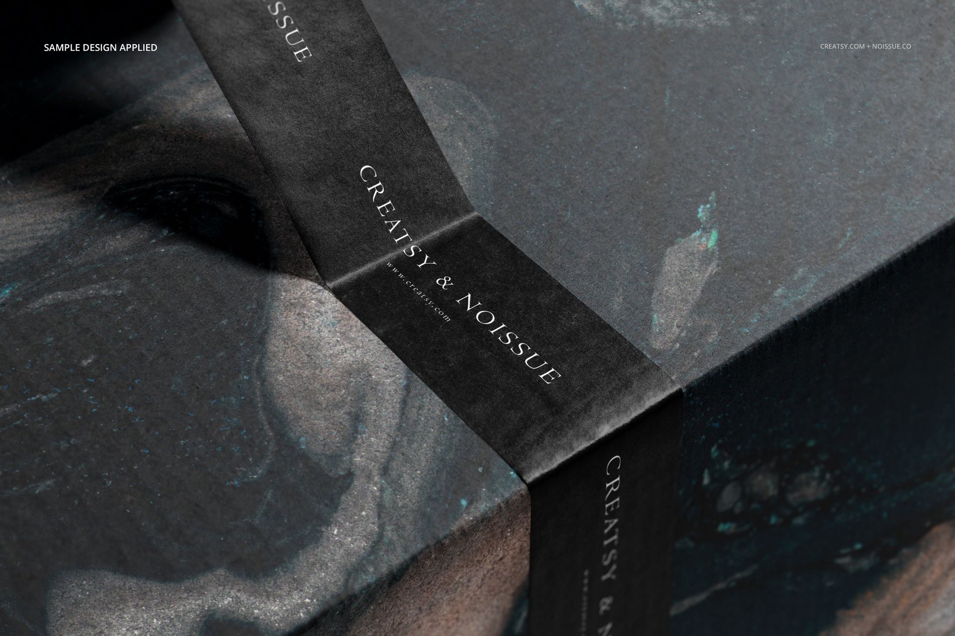 PSD mockup of a rectangular mailing box with black marbled surface, sealed with black tape displaying text.