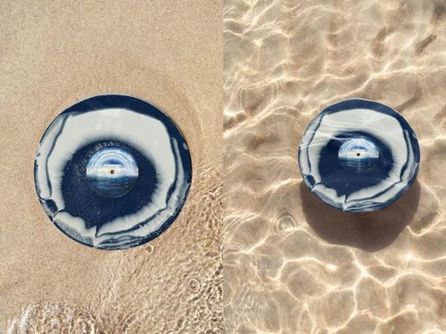 Top view of a blue and white vinyl record placed on sand and in shallow water, part of a PSD mockup set.