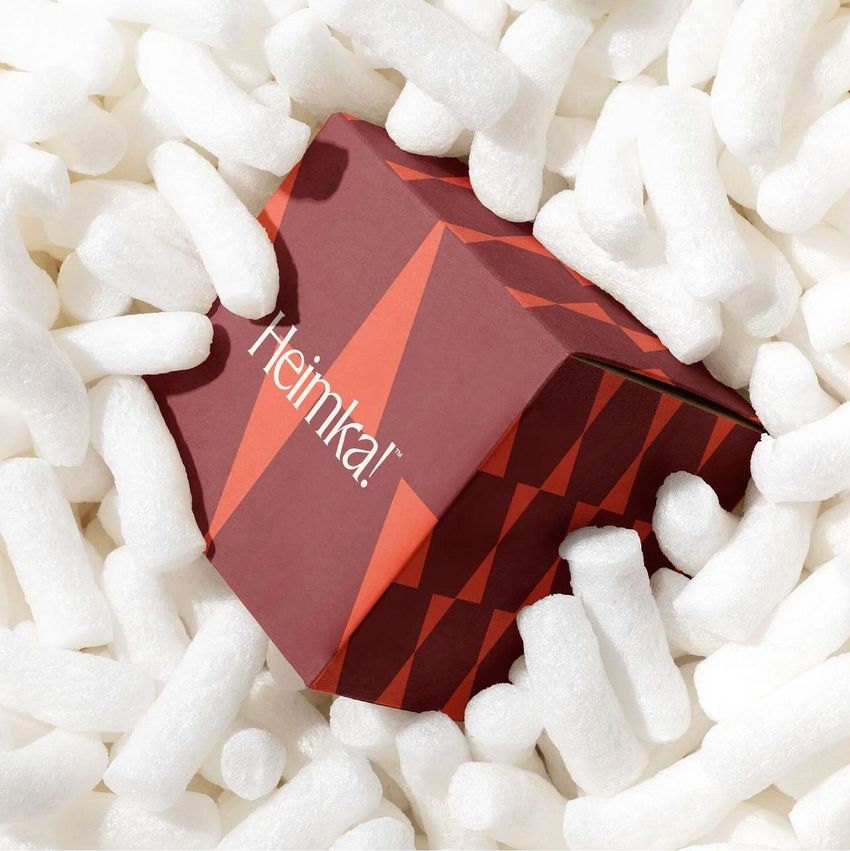 Kraft mailer mockup featuring a red box with geometric patterns and visible text, surrounded by white packing peanuts.