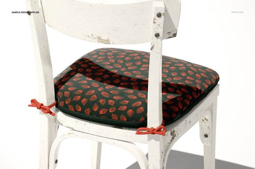 PSD mockup of a distressed white chair with a green cushion decorated with red leaves, viewed in bright lighting.