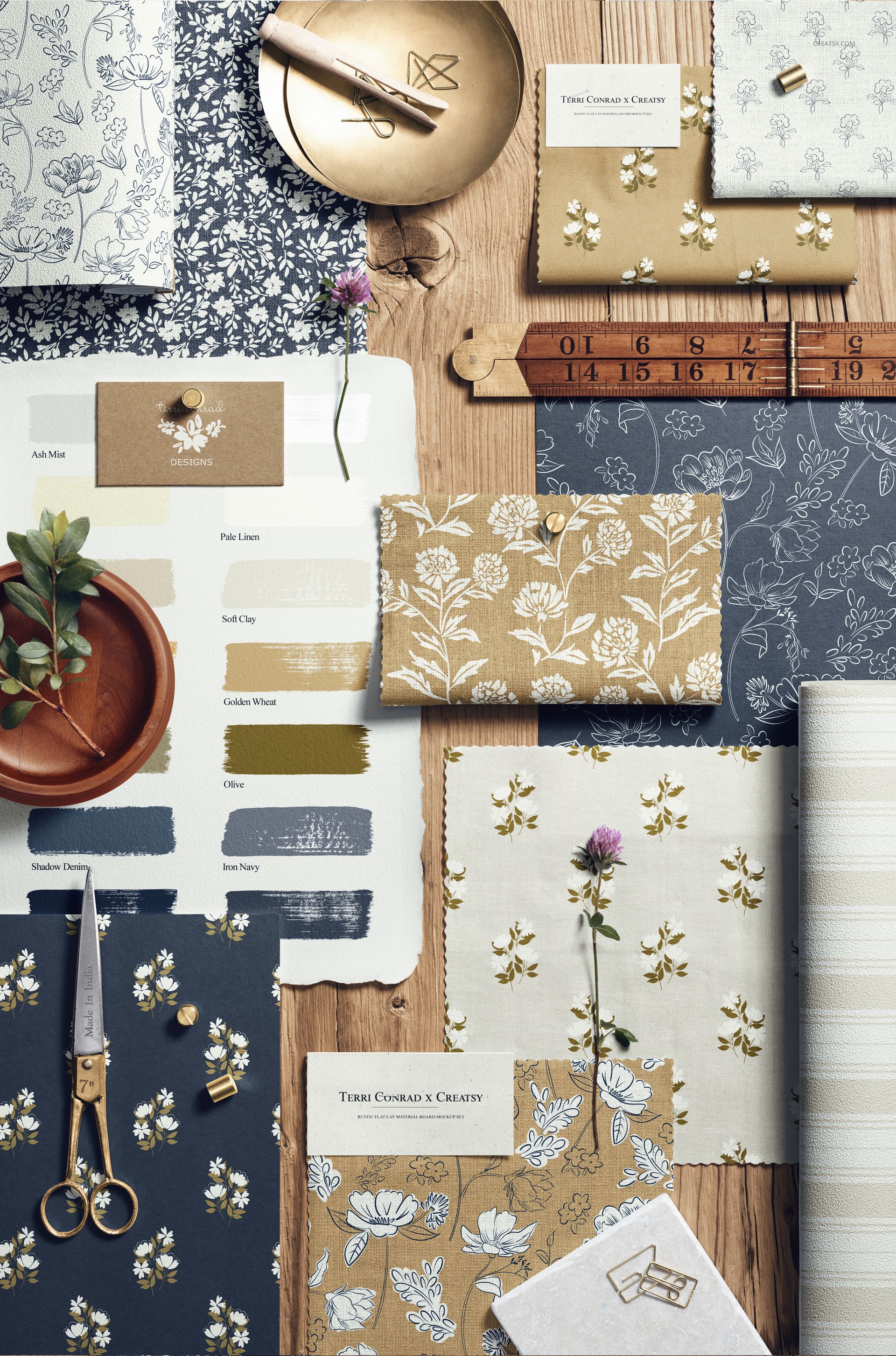 Rustic moodboard PSD mockup displaying floral fabric samples, envelopes, and art materials arranged on wood.