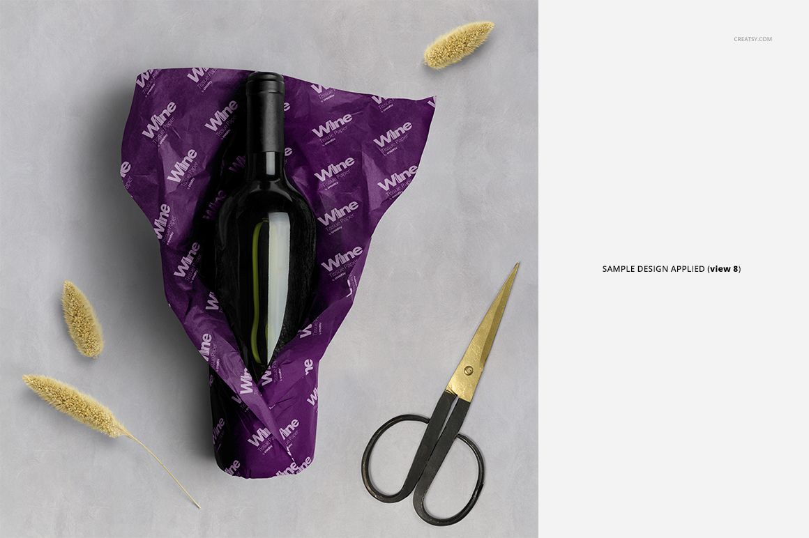 PSD mockup featuring a wine bottle wrapped in purple tissue paper with white lettering, surrounded by props.
