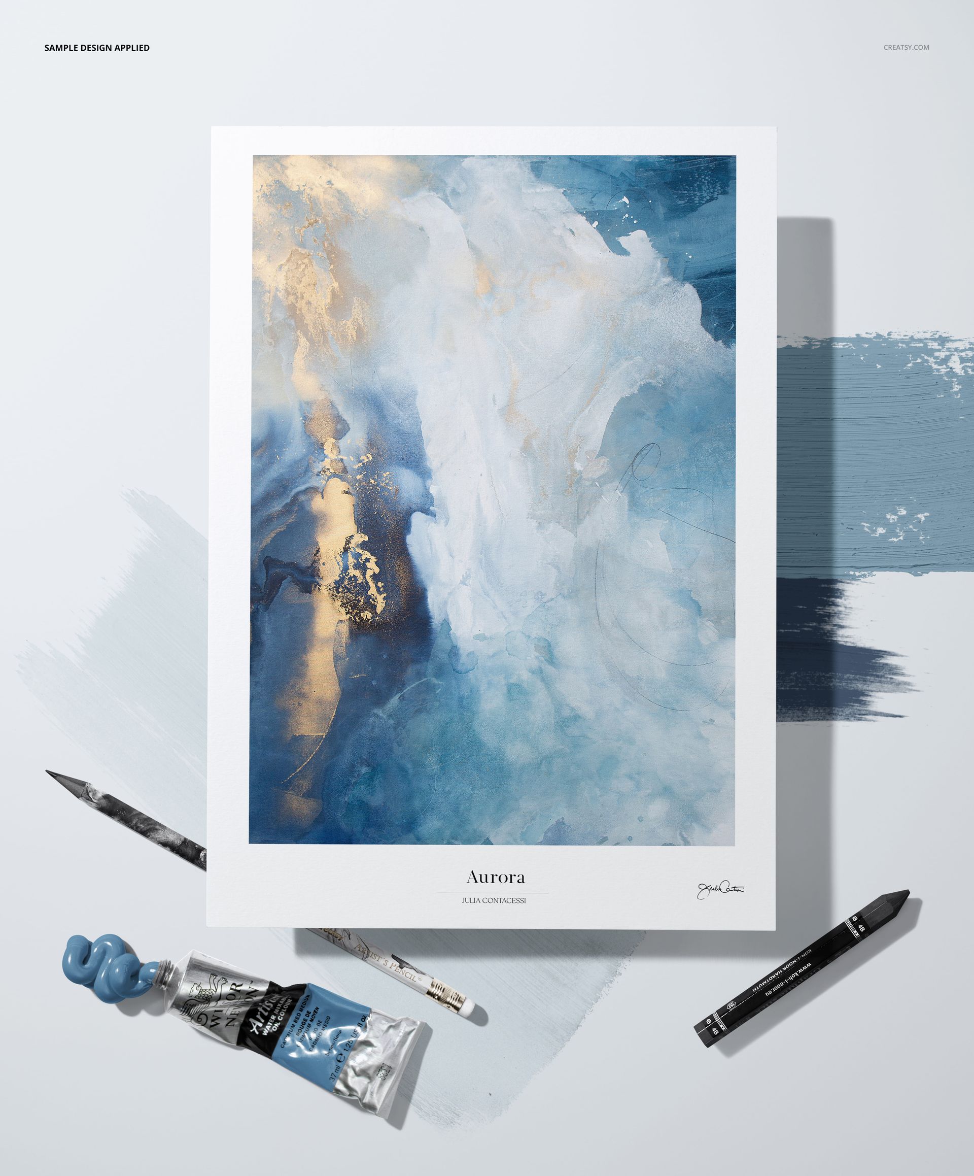 Textured paper mockup featuring an abstract blue and gold painting, shown from a top view with art supplies nearby.