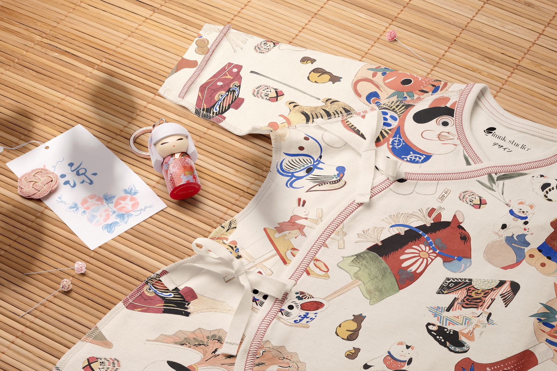 Organic cotton baby kimono bodysuit mockup featuring playful patterns, shown from a top view on a bamboo mat.