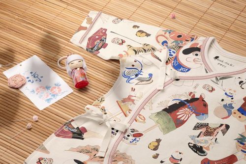 Organic cotton baby kimono bodysuit mockup featuring playful patterns, shown from a top view on a bamboo mat.