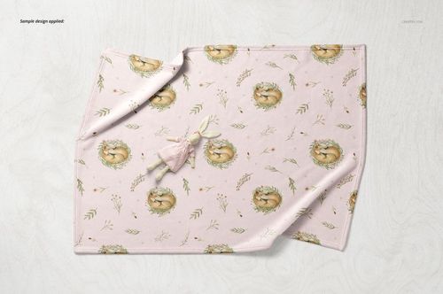 Soft fleece baby blanket mockup featuring a pastel pink fabric with animal and leaf patterns, top view on a light surface.