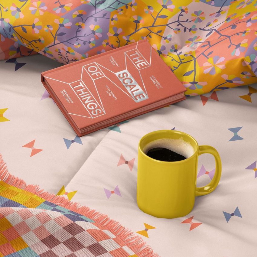 Microfiber comforter mockup featuring a colorful geometric and floral pattern, with a yellow mug and a book on a bed.