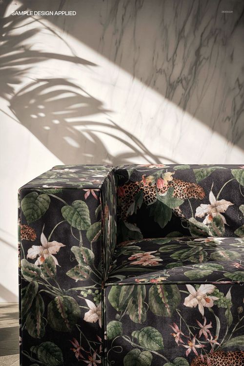 PSD mockup showing a velvet sofa with green leaves, flowers, and leopard print, illuminated by natural light and shadows.