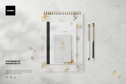 PSD mockup featuring a stationery set with notebooks, pens, and paper clips displayed on a white floral background.