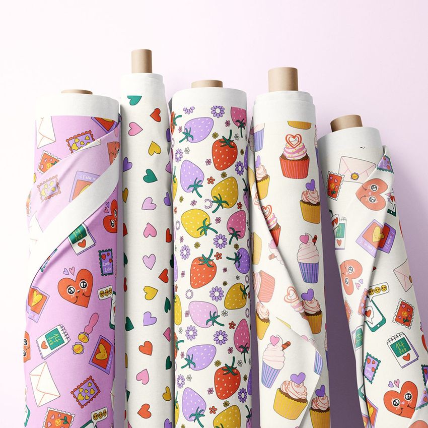 Fabric rolls mockup featuring five upright rolls with colorful Valentine-themed patterns, including hearts, strawberries, and cupcakes on a light background.