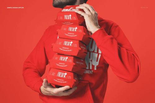 PSD mockup showing a person gripping multiple red burger packaging boxes, with a vibrant monochrome red scene.