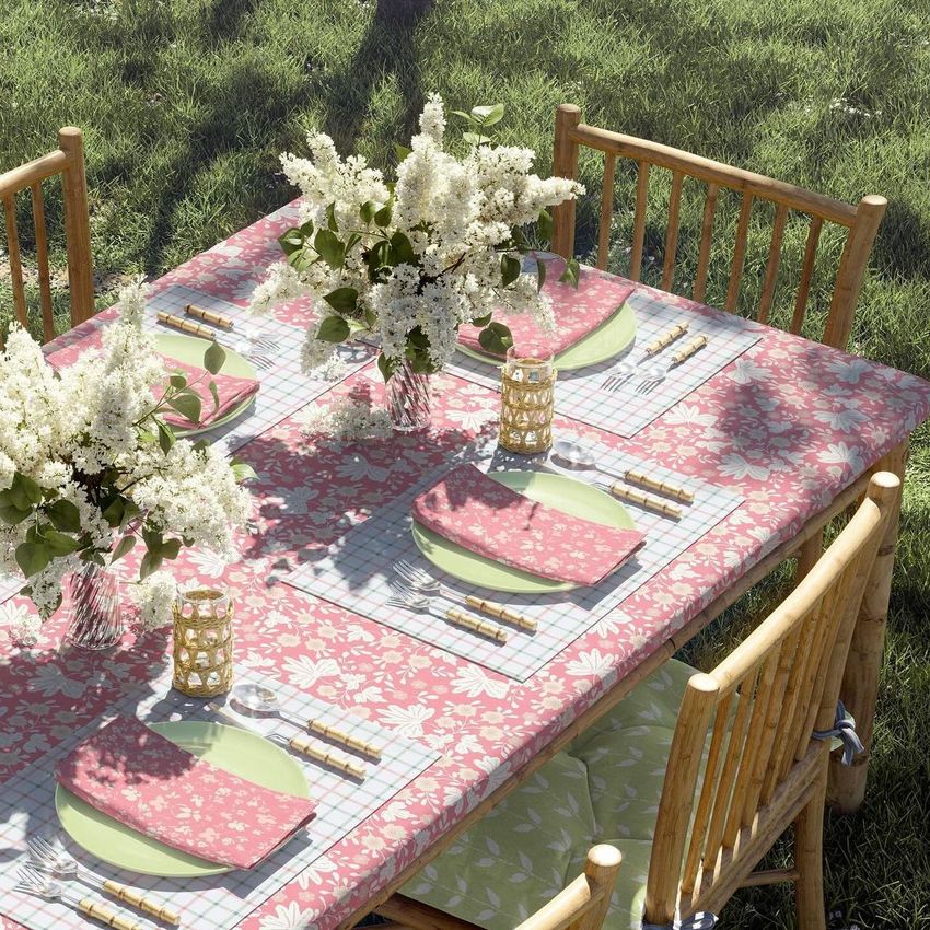 Tablecloth napkins placemat mockup showing a garden table set with floral tablecloth, pink napkins, and white flower centerpieces.