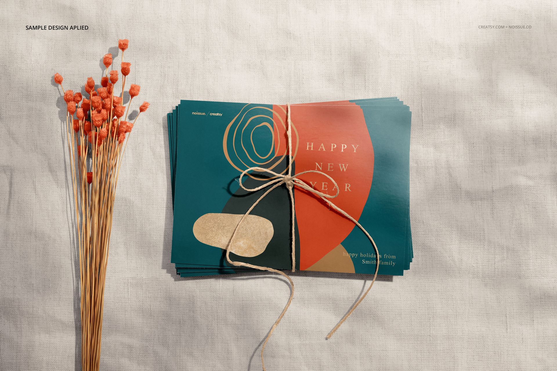 Front view of a bundle of mockup cards featuring geometric patterns in teal and coral, placed beside dried flowers.