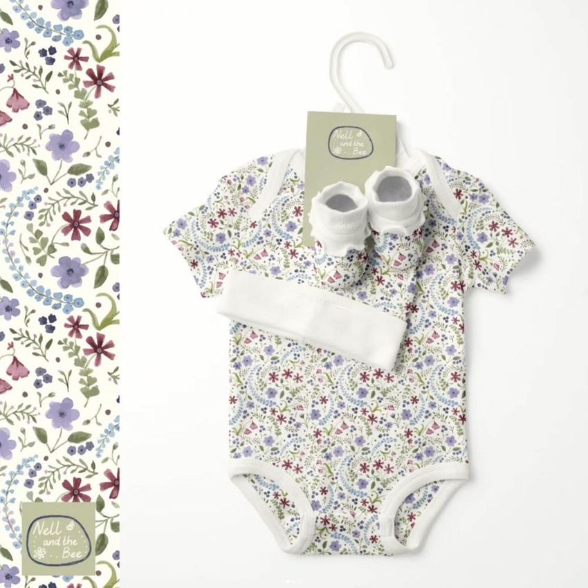 Kids & babies onesie mockup with matching hat and booties, featuring a floral pattern in soft pastel colors on a white background.