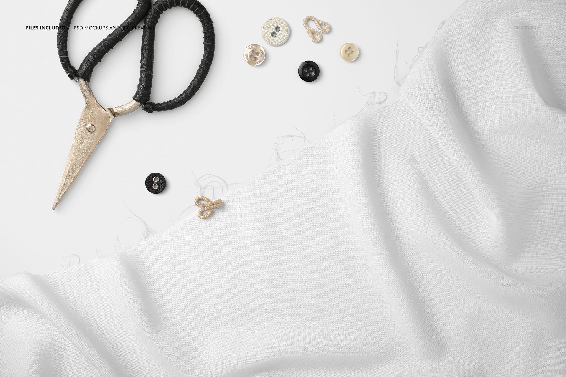 Wrinkled white textile mockup with scattered sewing tools like scissors, buttons, and hooks on a light background.