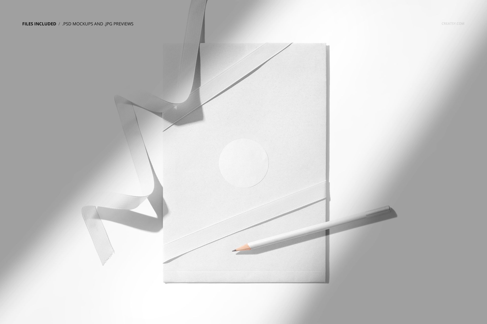 White stationery envelope mockup with ribbon details, a round sticker, and a pencil displayed on a sunlit surface.