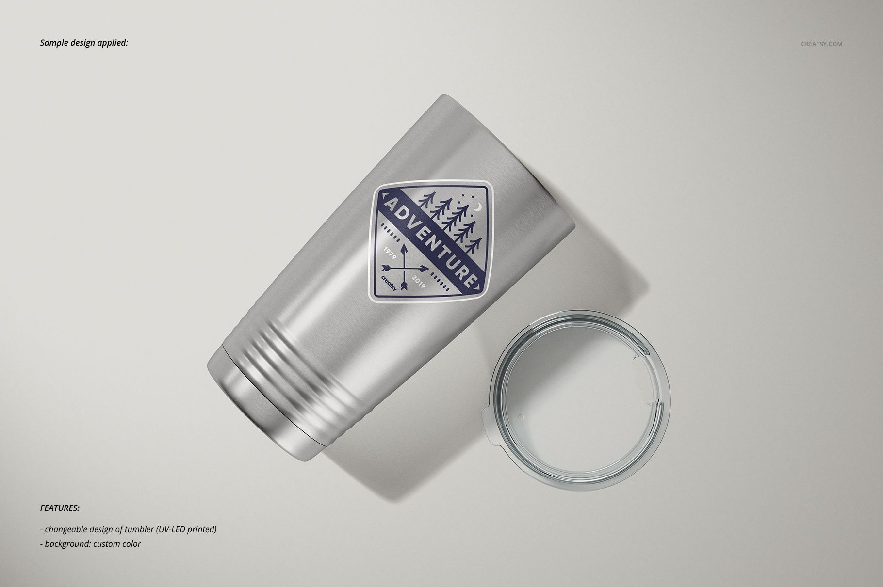 Stainless steel tumbler with a geometric mountain and tree design, shown from a top angle next to a clear plastic lid.